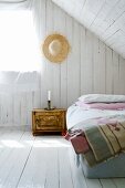 Simple attic bedroom with white-painted boards on walls and floor