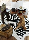 Geschnitzte Holztischchen mit afrikanischer Deko auf Zebrafell