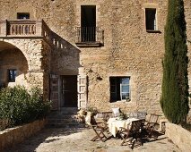 Essplatz auf sonniger Terrasse eines traditionellen, spanischen Natursteinhauses