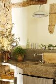 Concrete kitchen counter with stone sinks and vintage lamp against old masonry