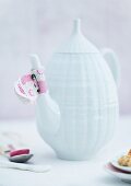 Fabric with daisy pattern as drip-catcher on white china teapot