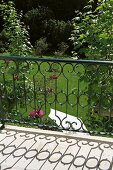 Metal balcony balustrade of curved wrought iron rods and view into well-tended garden