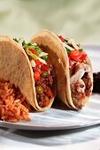 Zwei geschichtete Tacos, eins mit Rindfleischfüllung, eins mit Hähnchen, Reisbeilage