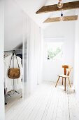 Dressing room with translucent curtain and wooden chair in front of window in attic room