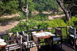 Gedeckte Tische auf Terrasse eines Restaurants und Blick auf Flusslandschaft