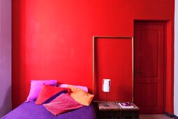 Betörende Rot- und Lilatöne in einfach ausgestattetem Schlafraum
