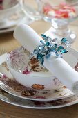 Festive place setting with floral crockery and linen napkin in beaded napkin ring