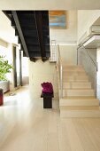 Offener, moderner Wohnraum mit Treppenaufgang aus hellem Holz