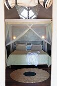 Runder Teppich auf Holzparkett und Doppelbett unter Moskitobaldachin in geräumigem Schlafzelt
