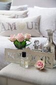 Roses, perfume and silver vase on bedside table