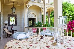 Set table with elegant candle lanterns on veranda of white, colonial-style building
