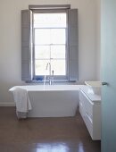 Blick durch offene Tür ins Designerbad auf freistehende Badewanne am Fenster