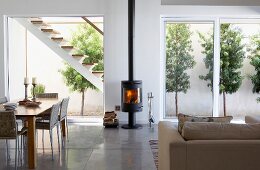 Dining area and lounge chairs in front of log-burner against wall between terrace doors with view of external staircase and patio