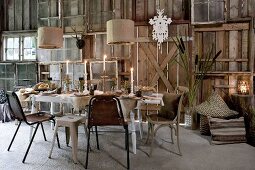 Festlich gesdeckter Tisch mit Kerzenlichtstimmung in scheunenartigen Raum und selbstgebaute Wand aus Vintage Fenstern