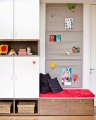 Seating area in child's bedroom with fabric wall hanging used as pinboard