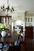 Long dining table and wooden chairs with ruched chair cushions in a open living room with a dignified and luxurious built-in kitchen