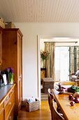 Dining room with wooden table opposite dresser and view into living room through wide, open doorway