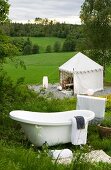 Vintage Badewanne auf einem Berghang und Blick auf zeltartigen Pavillon auf der grünen Wiese