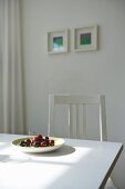 Plate of fresh cherries on white dining table in sunny kitchen