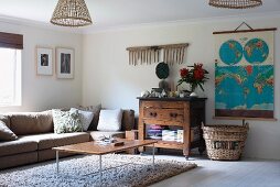 Modern coffee table on flokati rug and sofa below window next to rustic, half-height cabinet