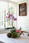 Blumendekoration auf Tisch vor geöffnetem Fenster