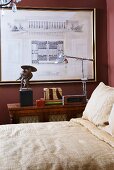 Bed linen bedding in natural colors from retro floor lamp and framed architectural drawing on dark red wall