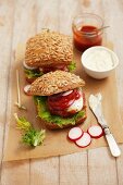 Hamburgers with tartare sauce, ketchup and radishes