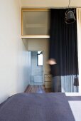 Blick über das Doppelbett in das Bad Ensuite hinter dunklem Vorhang