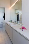 Minimalistischer Waschtisch vor großem Wandspiegel im weissen Bad
