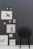 Black, mesh-like plastic chair against black wall next to framed pictures of animals