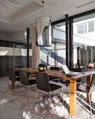 Moderner Tisch aus Holz und Stühle mit Lederbezug vor Fensterfront in zeitgenössischem Wohn- und Esszimmer