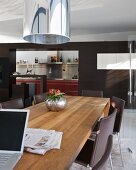 Modern wooden table and chairs in living room with black-painted partition and wide doorway leading to kitchen