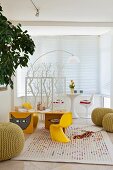 Child's desk with classic chairs, knitted poufs and play rug; white, retro play area behind a floral screen