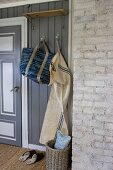 Aufgehängte Tasche und Wäschesack an Garderobenhaken im Hausflur mit grauer Holzverkleidung
