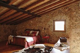 Double bed under sloping roof of Spanish stone house