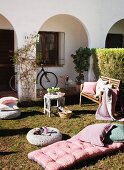 Sunbathing in a front yard with pillows and patio furniture pads on the grass in front of a Mediterranean home with an arcade