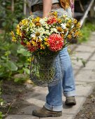 Woman carrying summer bouquet of dahlias, alstroemeria and rudbeckia