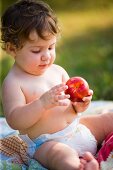 A small child investigating a peach