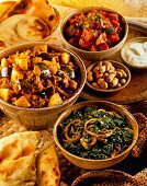 Aubergine and potato curry, spinach curry with onions, sweet potatoes, and naan bread (India)