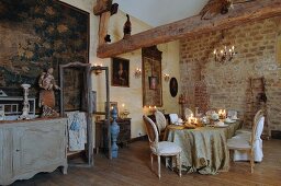 Rococo romantic atmosphere within old walls - long candlelit table festively set and surrounded by antique flea-market finds