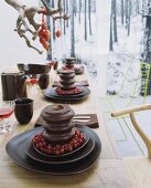 A table laid for dessert - Baumkuchen (German layer cakes) with trusses of redcurrants on a set of dark brown ceramic dishes