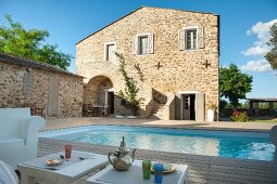 Chillen auf schattiger Terrasse - Getränke auf Beistelltischen vor Pool im Innenhof einer mediterranen Wohnanlage