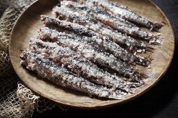 Anchovies covered with sea salt on a wooden plate