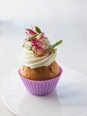 A cupcake topped with cream cheese, wild asparagus and beetroot sprouts