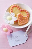 Herzplätzchen mit Zuckerguss, essbaren Papierblüten und Liebesbotschaft