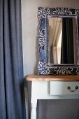 Mirror with ornate metal frame on rustic console table