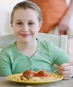 Mädchen isst Spaghetti mit Fleischbällchen