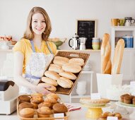 Frau mit frisch gebackenen Brötchen in einer Bäckerei