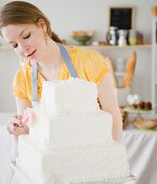 Frau bestreicht Hochzeitstorte mit weisser Glasur