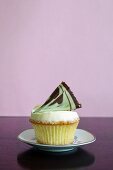 A cupcake topped with a fan of chocolate and pistachio